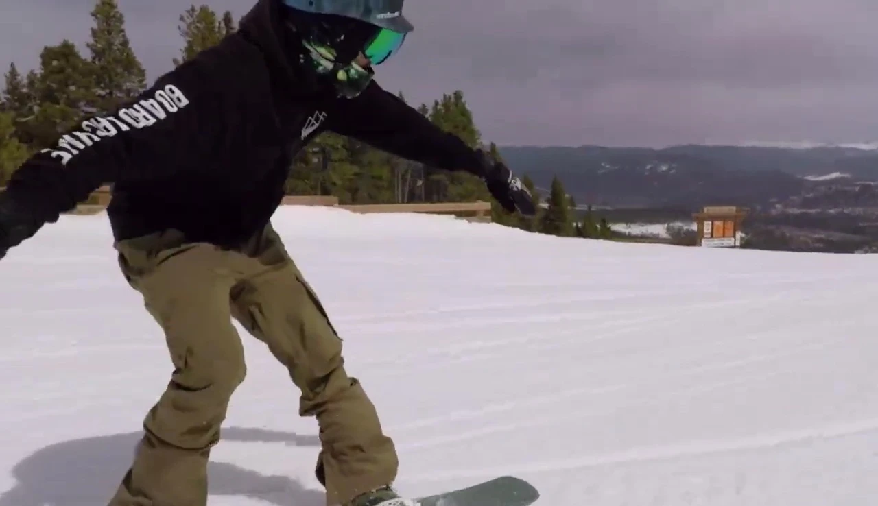 The snowboarder riding the rocker board down a groomed run.