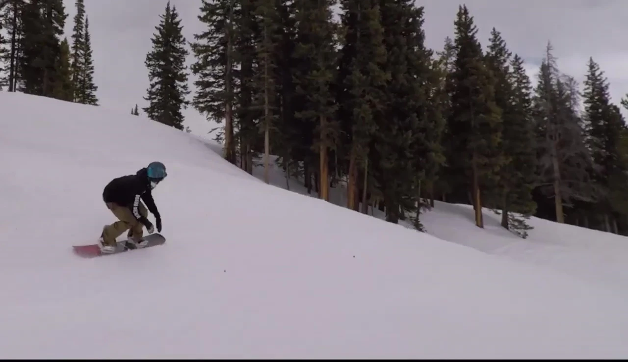 The snowboarder riding the camber board through the park.