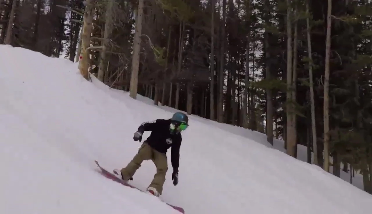 The snowboarder performing a turn on the camber board, emphasizing its precision and power.
