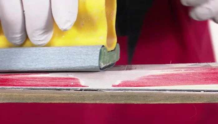 Sand the body filler patch again using medium grit sandpaper on a sanding block. Use sandpaper wrapped around a flat object to finish the side walls.