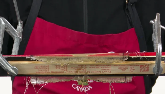 Trim the excess material from the edges of the ski using a steel guide to protect the ski base. Sand the edges flush.