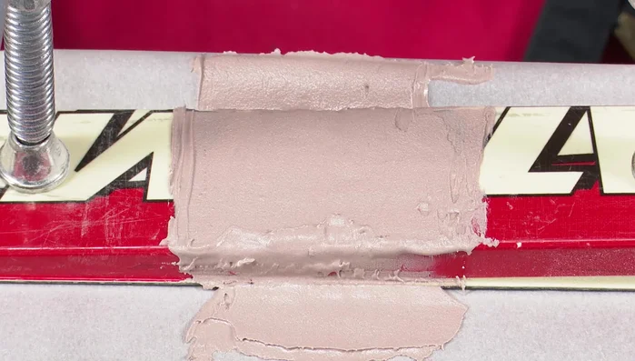 Use a petroleum jelly-coated steel scraper to further flatten and level the surface. Clamp and press down. Wait for curing.