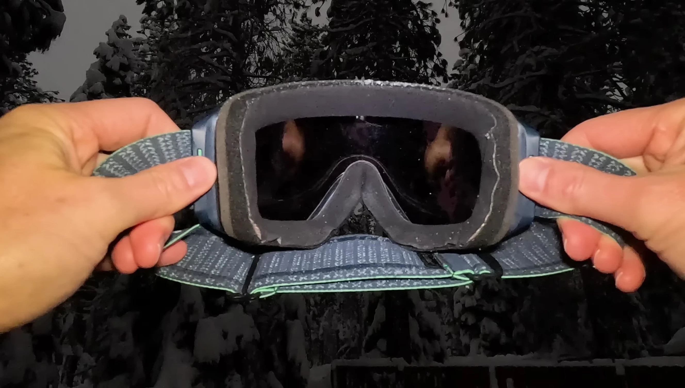 Close-up of a person trying on snowboard goggles, emphasizing the importance of proper fit.