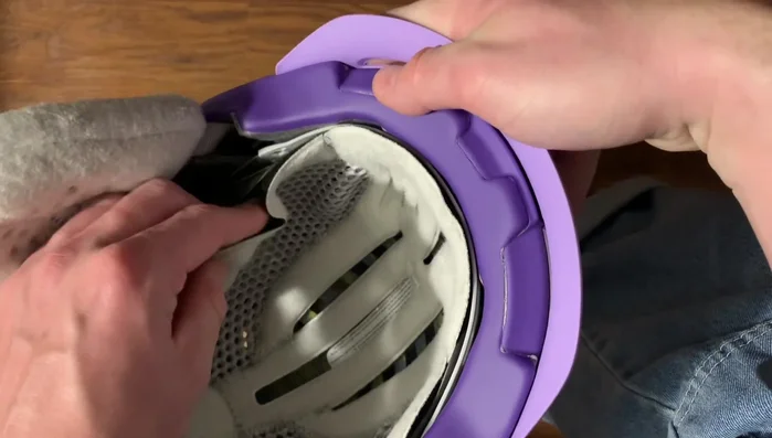 Slightly pull back the liner to expose the bow system (the mechanism that tightens the helmet).