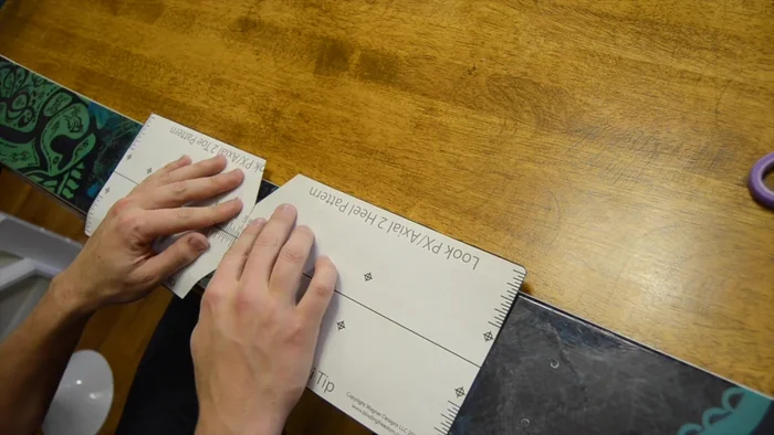 Use a punch or Phillips head screwdriver to make dimples on the top sheet of the ski, centered on the template's x's.