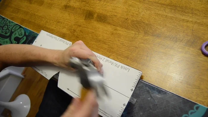 Use a punch or Phillips head screwdriver to make dimples on the top sheet of the ski, centered on the template's x's.