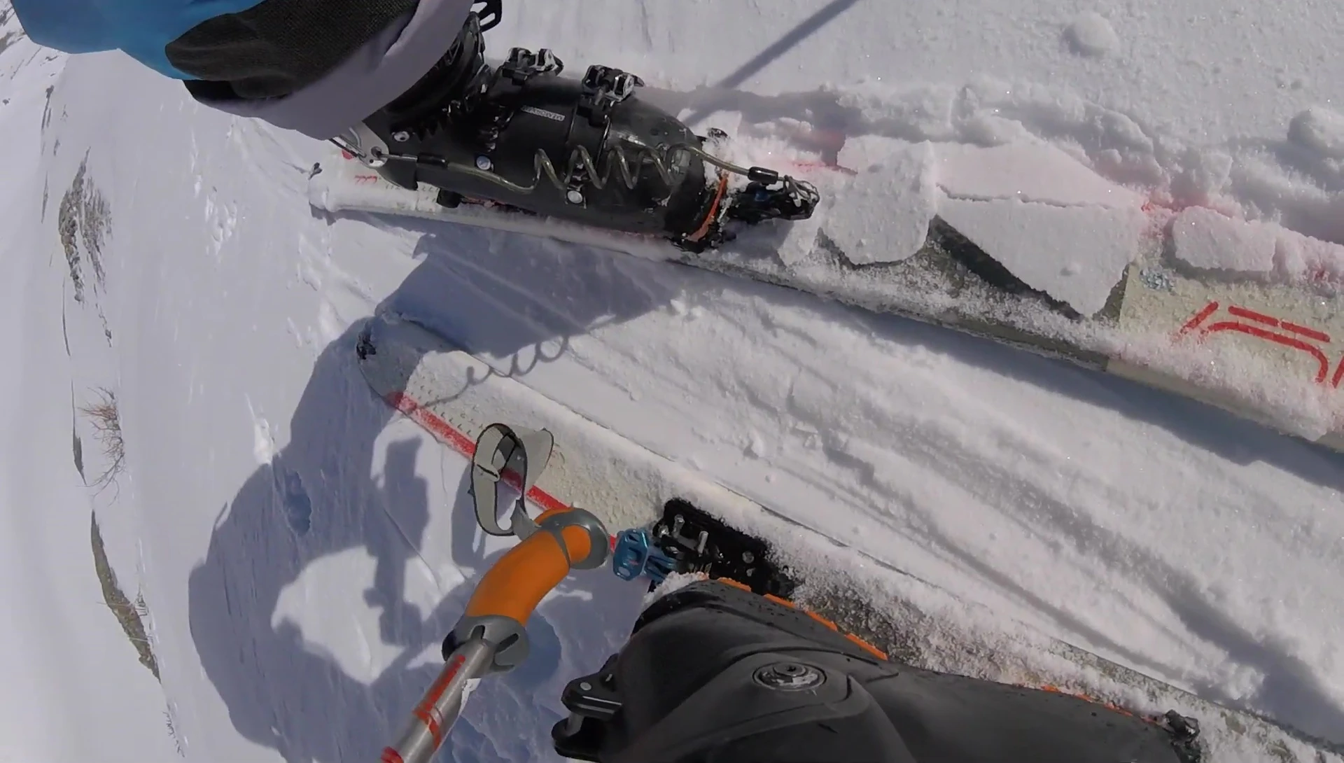 The speaker using their ski pole to adjust the binding