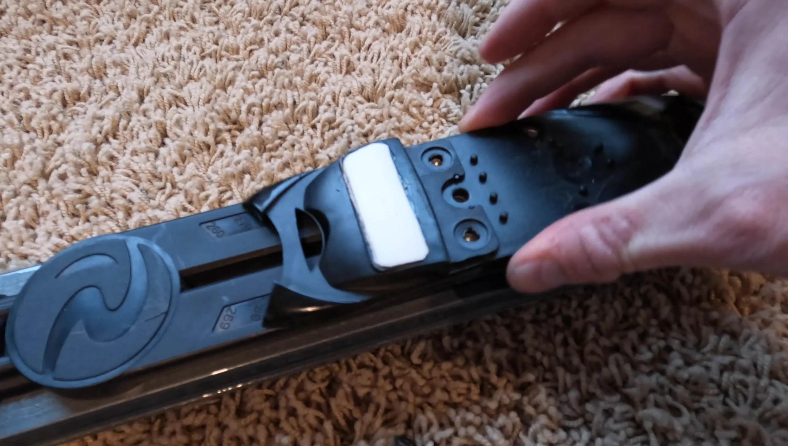 The bracket that adjusts the boot length range, showing how to align it with the screw holes