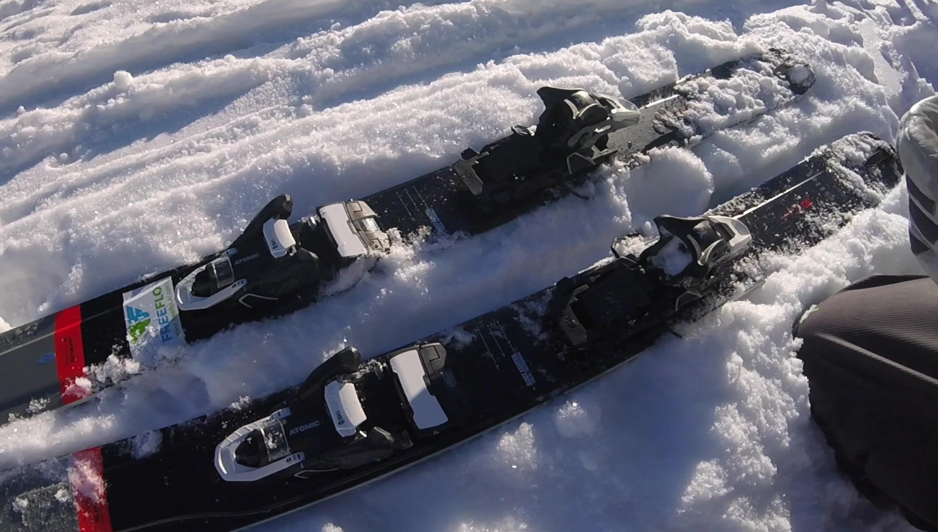 The skier demonstrating the initial step of flipping down the lever to switch to uphill mode.