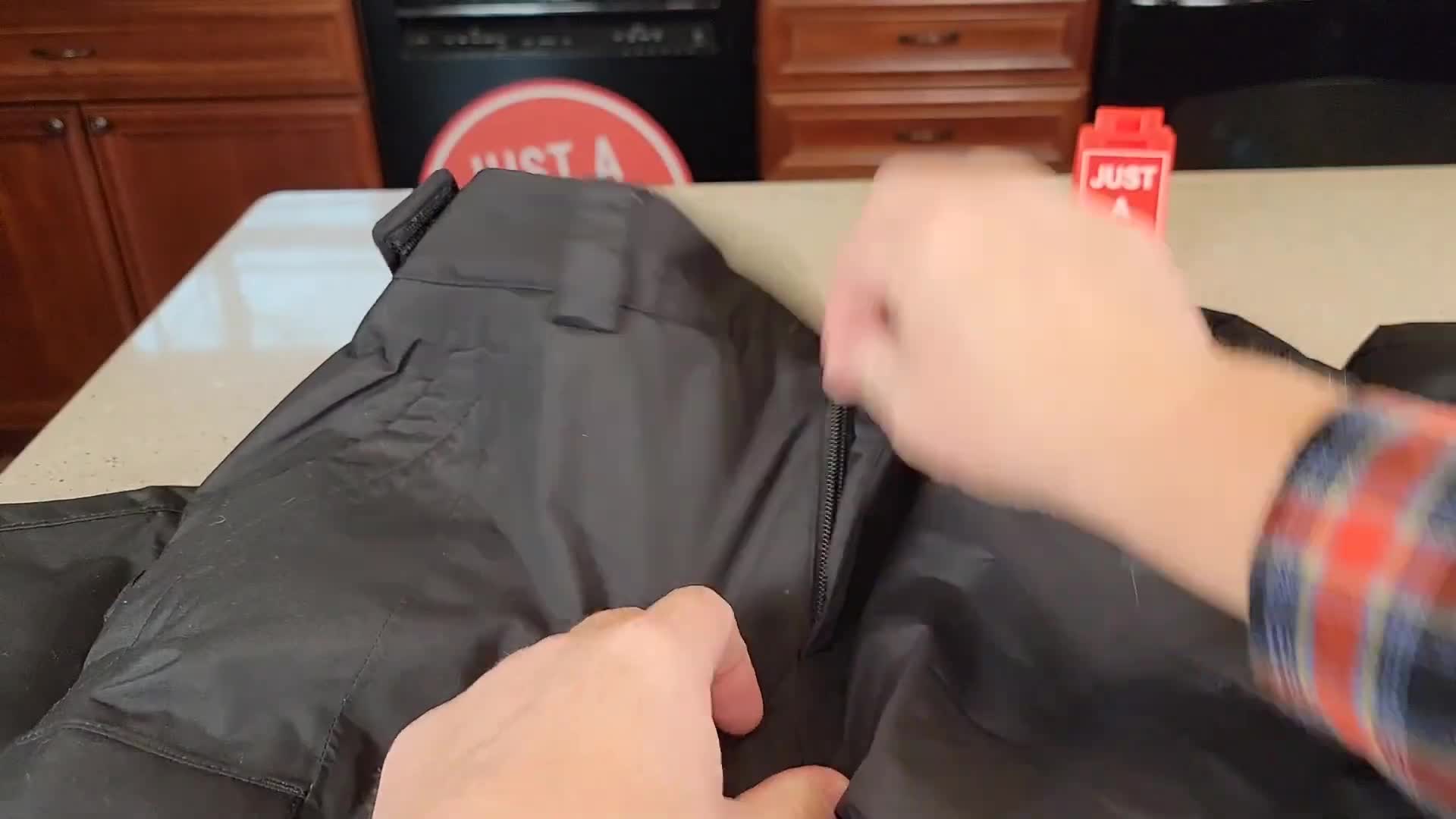 Close-up of the zipper and button closure on the waist of the snow pants.