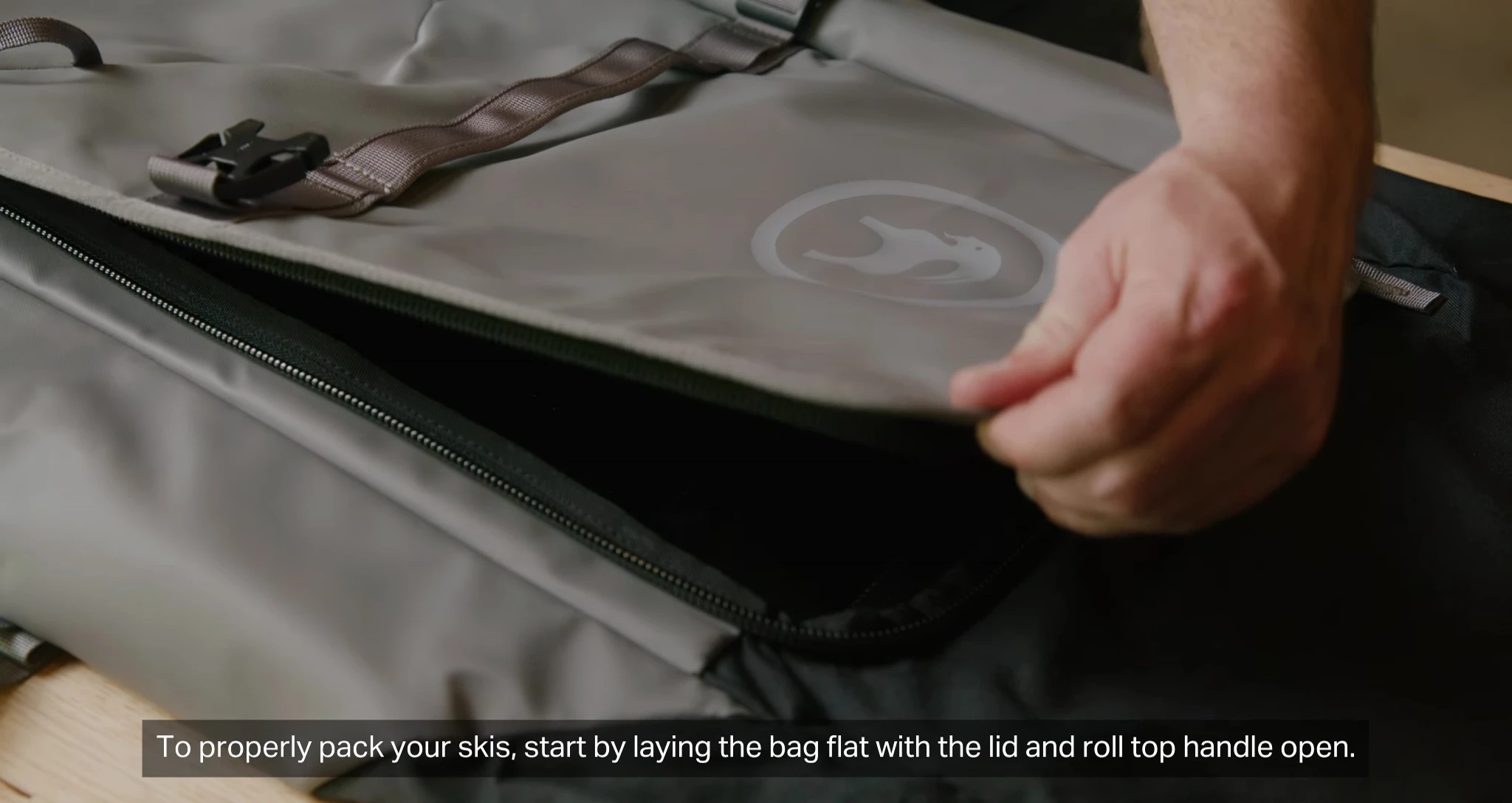 Laying the bag flat and opening the lid and roll-top handle.