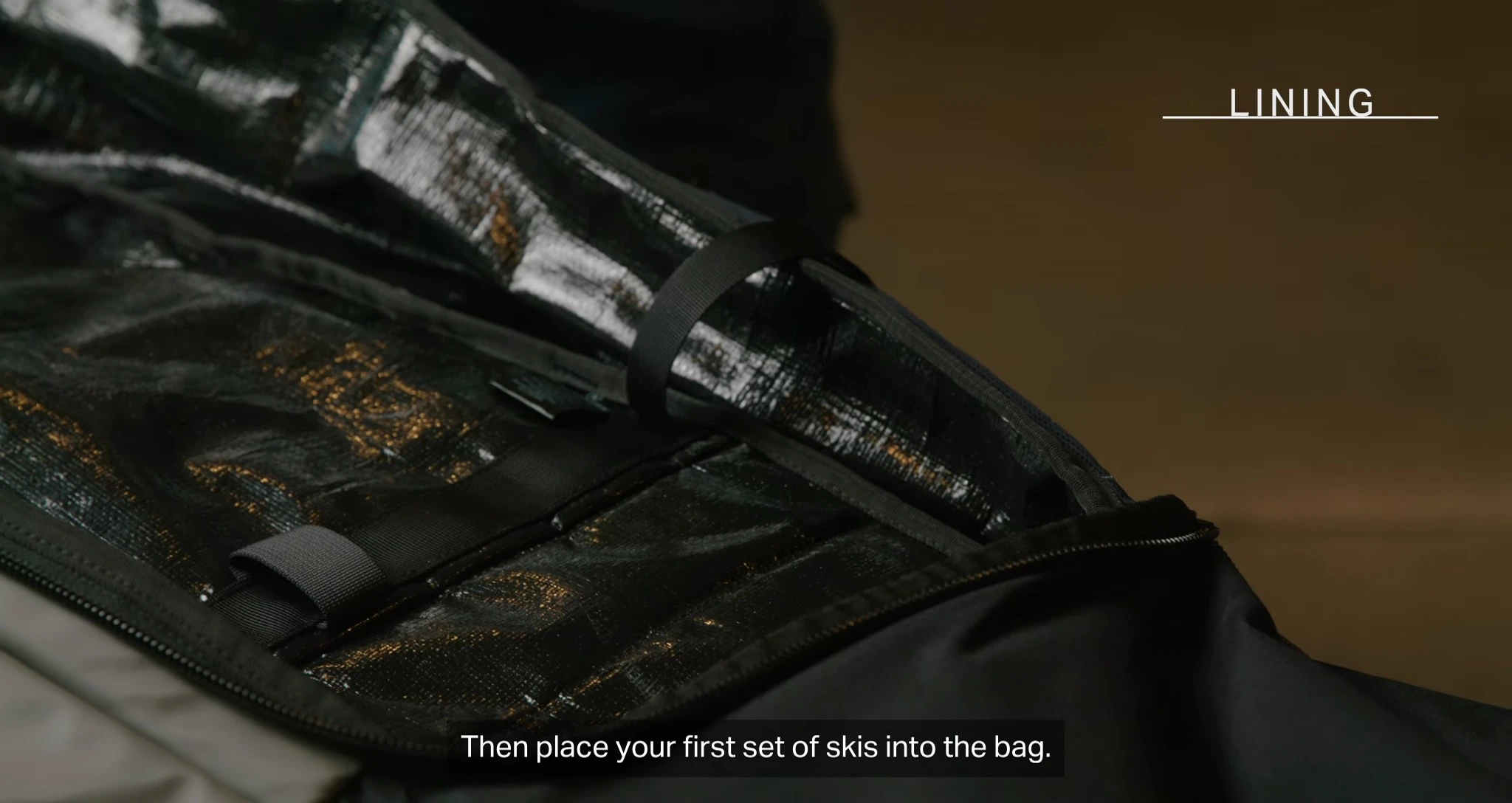 Placing the first pair of skis into the bag.