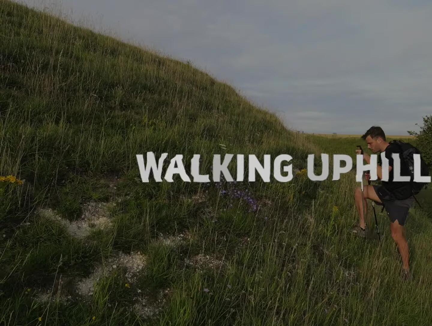 Hiker adjusting trekking pole length for uphill walking