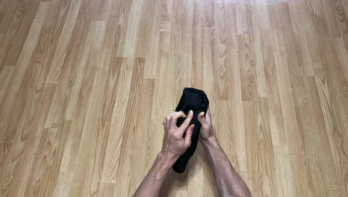 Use your hand to pull the cuff (from step 3) around the rolled coat, creating a 'coat burrito'.