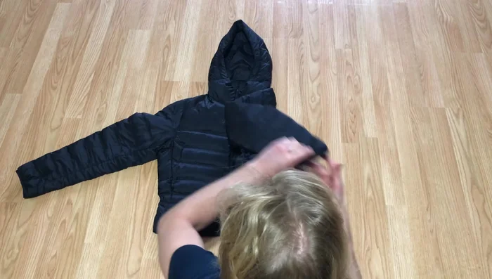 Fold the other side over the previous fold, and fold the sleeve back across and up as well, keeping it in line with the coat.