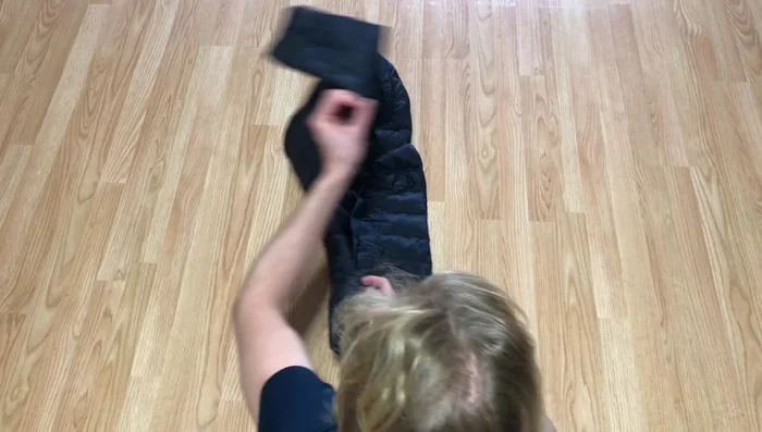 Fold the other side over the previous fold, and fold the sleeve back across and up as well, keeping it in line with the coat.