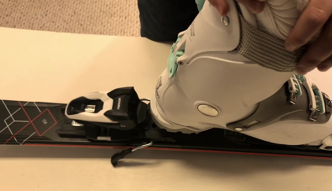 Close-up of a professional adjusting a specific part of the ski binding.